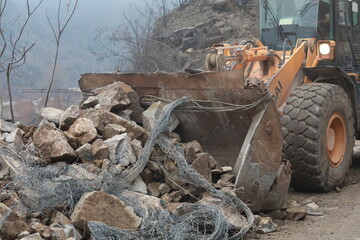 Elisseina, Bulgaria - February 2, 2021: Heavy chain and wheeled equipment clears the highway after a rock collapse near Elisseina station, Bulgaria