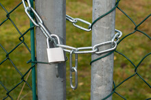 A Padlock Hanging At A Chain-link Fence