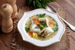 Ukha (Russian Fish Soup). White fish in a clear broth with diced root vegetable served in white plate on wooden table. Selective focus.