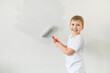 © Iryna Dincer - Happy smiling  toddler child painting wall looking to the camera.. The concept of moving to a new apartment. Cute little boy painting wall in his room.