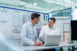 © Daniel Ingold/Westend61 - Business people with laptop on desk planning against bulletin board in factory