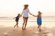 © steve brookland/Westend61 - Children holding hands of mother while running at beach during sunset