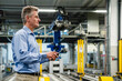 © Daniel Ingold/Westend61 - Male entrepreneur looking around while holding digital tablet in factory