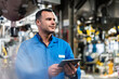© Daniel Ingold/Westend61 - Smiling technician looking away while holding digital tablet in industry