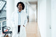 © Joseffson/Westend61 - Smiling young male doctor standing with hands in pockets while looking away at hospital corridor