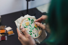 Young Woman's Hands Embroidering Cloth In Shape Of Lemon Tree