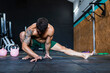 © Miguel Frias/Westend61 - Shirtless muscular young man stretching on floor in gym