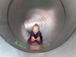 © Albrecht Wei√üer/Westend61 - Smiling girl sliding in tube while looking away at playground