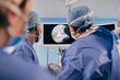 © Sr.Stocker/Westend61 - Professionals monitoring surgery on computer screen while standing in operating room