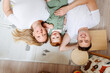 © Katharina und Ekaterina/Westend61 - Portrait of happy family with baby daughter lying on floor at home