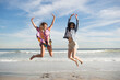© Jamie Grill/Tetra Images - Two young women jumping on beach