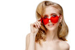 © Miramiska - Beautiful girl in red plastic glasses in the shape of a heart. Woman on February 14th, Valentine's Day. A model with amazing makeup and hair.