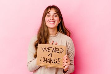 Wall Mural - Young caucasian woman holding a We need a change placard isolated laughs out loudly keeping hand on chest.