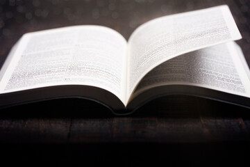 Poster - A Bible Open on a Rustic Wooden Table with Pages Blowing Open