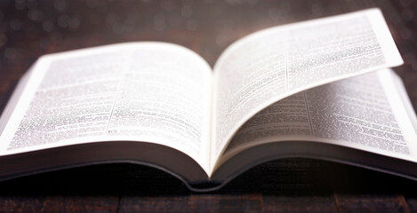 Poster - A Bible Open on a Rustic Wooden Table with Pages Blowing Open