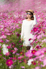 Wall Mural - Beautiful Asian woman wearing white dress in cosmos flowers field blooming in the garden.