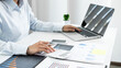 © Orathai - Asian female accountant sits at their desks and calculates financial graphs showing results about their investments, plan a successful business growth process