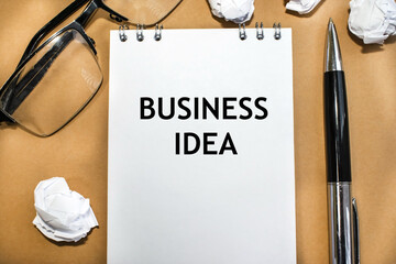 The inscription business idea on a notebook with a white sheet. Pen glasses for vision and crumpled sheets of paper. Business concept