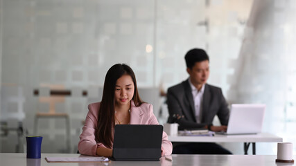 Asian businesspeople working with laptop and sitting together in modern office.