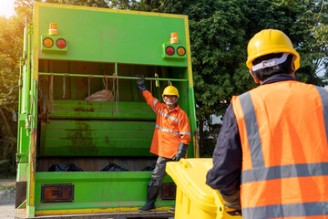 Wall Mural - Two refuse collection workers loading garbage for trash removal.