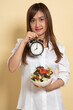 Young Asian woman with clock and salad.