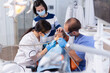 © DC Studio - Parent comforting daughter in the course of dental treatment in dentist office. Mother with her kid in stomatology clinic for teeth examine using modern instruments.