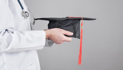 Wall Mural - Caucasian doctor holding graduation hat. Medical education