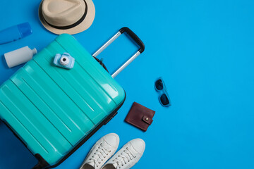 Canvas Print - Flat lay composition with suitcase and travel accessories on light blue background, space for text. Summer vacation