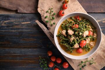 Northern Thai food (Kaeng Sa Lae), Spicy soup Broussonetia Kurzii with pork and tomatoes in a bowl on wooden background, Seasonal food in North Thailand