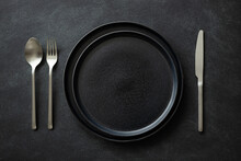 Empty Black Plates With Silver Cutlery On The Black Table. Top View.