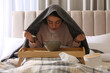 © New Africa - Woman with plaid doing inhalation above bowl on bed