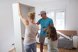 © astrosystem - Mother, father, and daughter assembling furniture in new apartment, moving in and being hardworking.