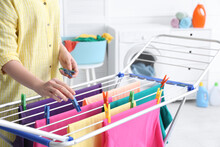 Woman Hanging Clean Laundry On Drying Rack In Bathroom, Closeup