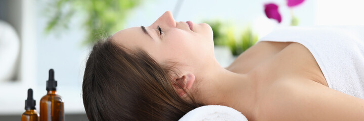 Wall Mural - Close-up of young beautiful woman laying on massage table in spa salon. Relaxed lady smiling and feeling happy after hard day. Take care of yourself. Relaxation and beauty day concept