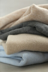 Stack of cashmere clothes on wooden table, closeup