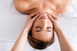 © LIGHTFIELD STUDIOS - top view of masseur doing facial massage to young client in spa salon