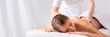 canvas print picture - masseur massaging pleased young woman on massage table in spa salon, banner