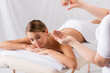© LIGHTFIELD STUDIOS - masseur holding glass container and pouring oil on hand near client lying on massage table and blurred background