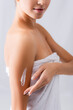 © LIGHTFIELD STUDIOS - cropped view of woman applying cosmetic cream on body on white