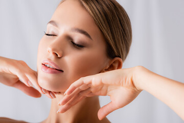 sensual young woman with closed eyes touching face on white