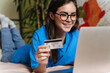 © Drobot Dean - Happy brunette girl holding credit card and working with laptop