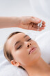 © LIGHTFIELD STUDIOS - beautician holding pipette and applying serum on face of client in spa salon