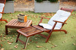 Wooden chairs in autumn garden. Vintage radio on table. Two deckchairs on green summer lawn on picnic. Lounge sunbed. Wooden garden furniture on grass lawn outdoor for relax. Backyard exterior.	