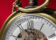 Pocket watch clock face, macro closeup on a red background with a shallow depth of field