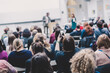© kasto - Male speaker giving presentation in lecture hall at university workshop. Audience in conference hall. Rear view of unrecognized participant in audience. Scientific conference event.