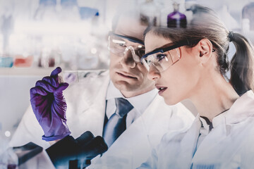 Poster - Attractive young scientist and her post doctoral supervisor looking at the microscope slide in the forensic laboratory.