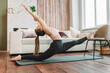 © Olga Rolencino - Young fit flexible woman wearing sportswear do stretching exercises in living room. Indoors workout. Training at home.