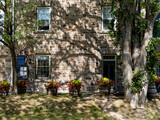Fototapeta  - outside of Old style restaurant with stone wall in the small town of Perth, Ontario. Plants decorations, vintage, trees and shadows