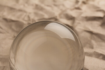 Crystal, transparent ball, sphere on  crumpled paper background.