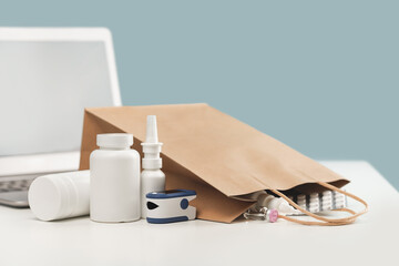 Wall Mural - Online pharmacy. prescription drugs and over the counter medication ready for delivery to customers. Pills and spray white mockup containers and buff paper bags over the laptop with pulse oximeter